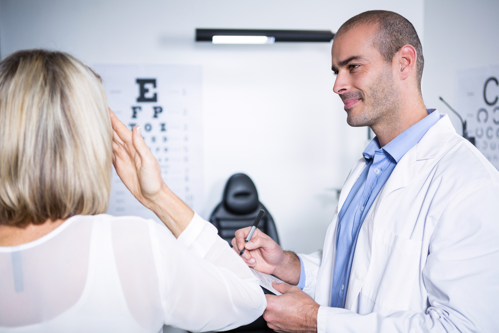 How to diagnose legal blindness. Male optometrist taking eye test of female patient in ophthalmology